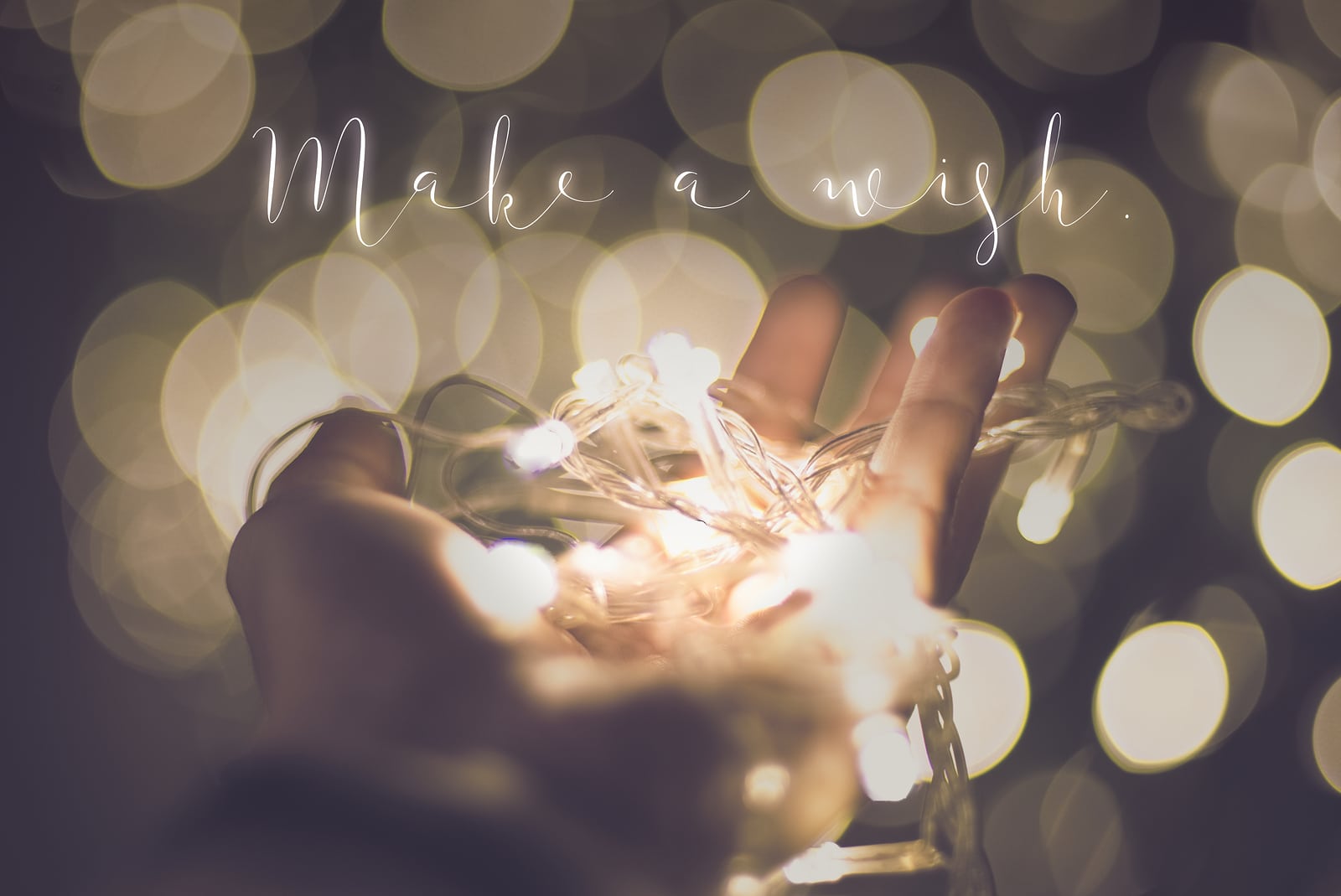 Make a wish word over hand with light bokeh in vintage filter,Holiday quote,christmas season.