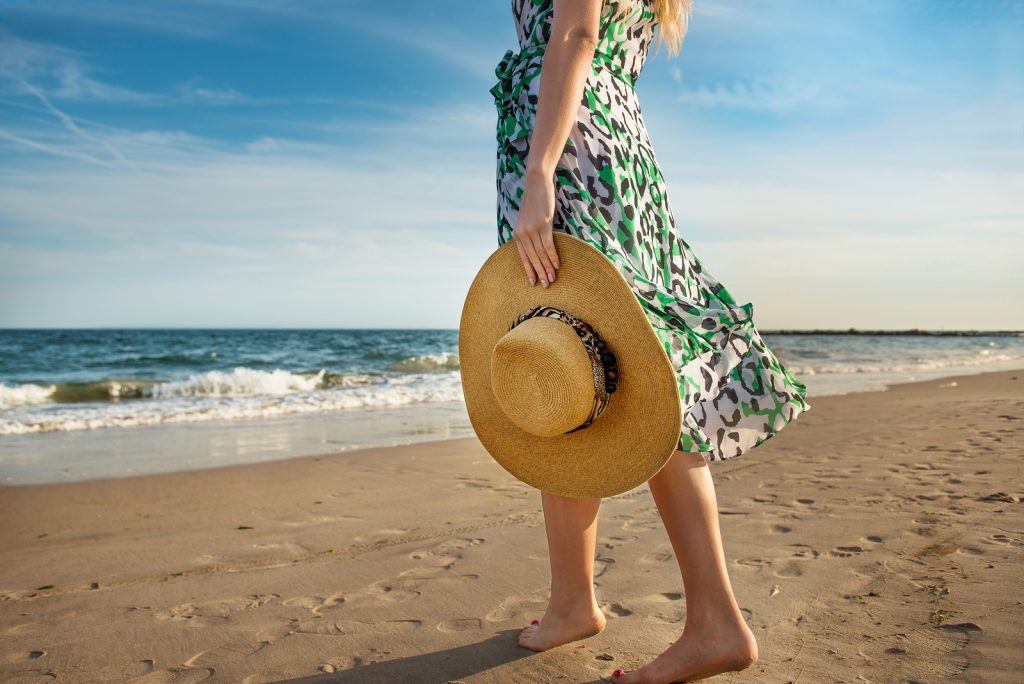 Barefoot woman walking on the ocean beach sand and enjoy the vacation during the tourist trip to the tropical island.