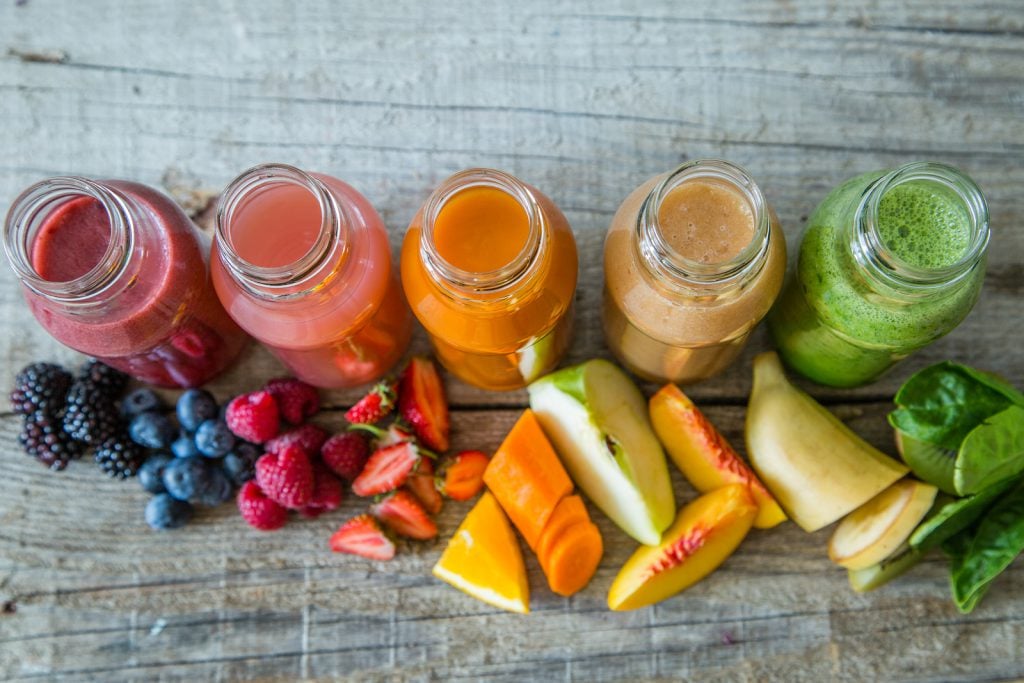Selection of colourful smoothies on rustic wood background, copy space