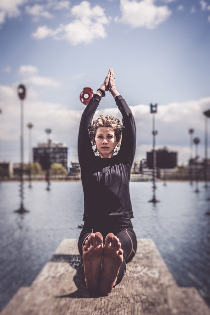 Woman doing yoga near lake in urban setting, La Defense, Paris