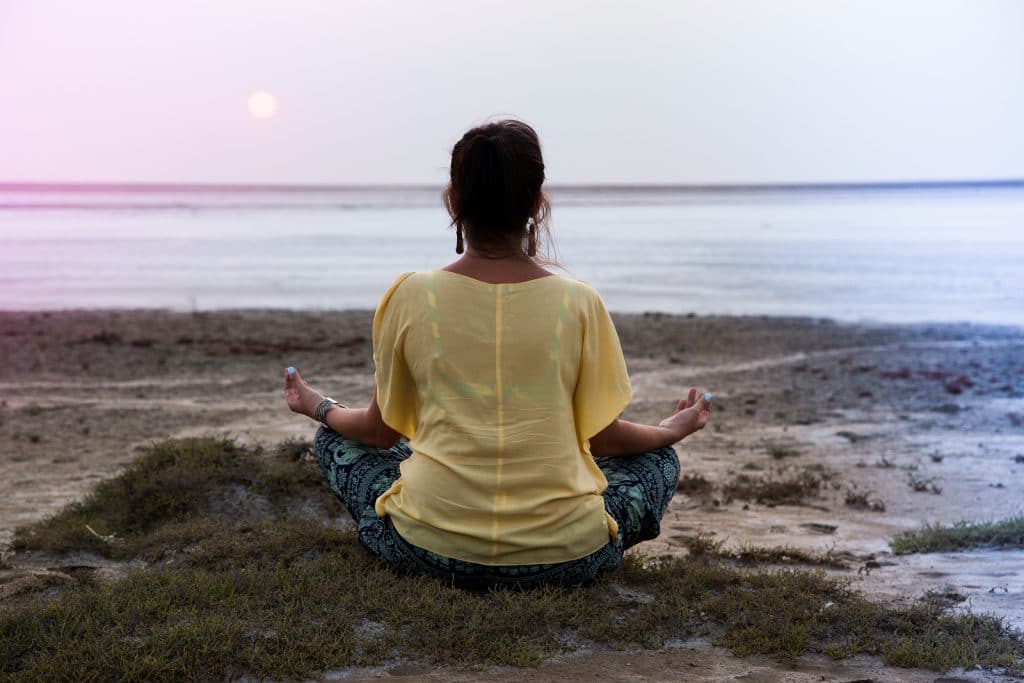 girl meditating at sunset. sits back looks at the sun.