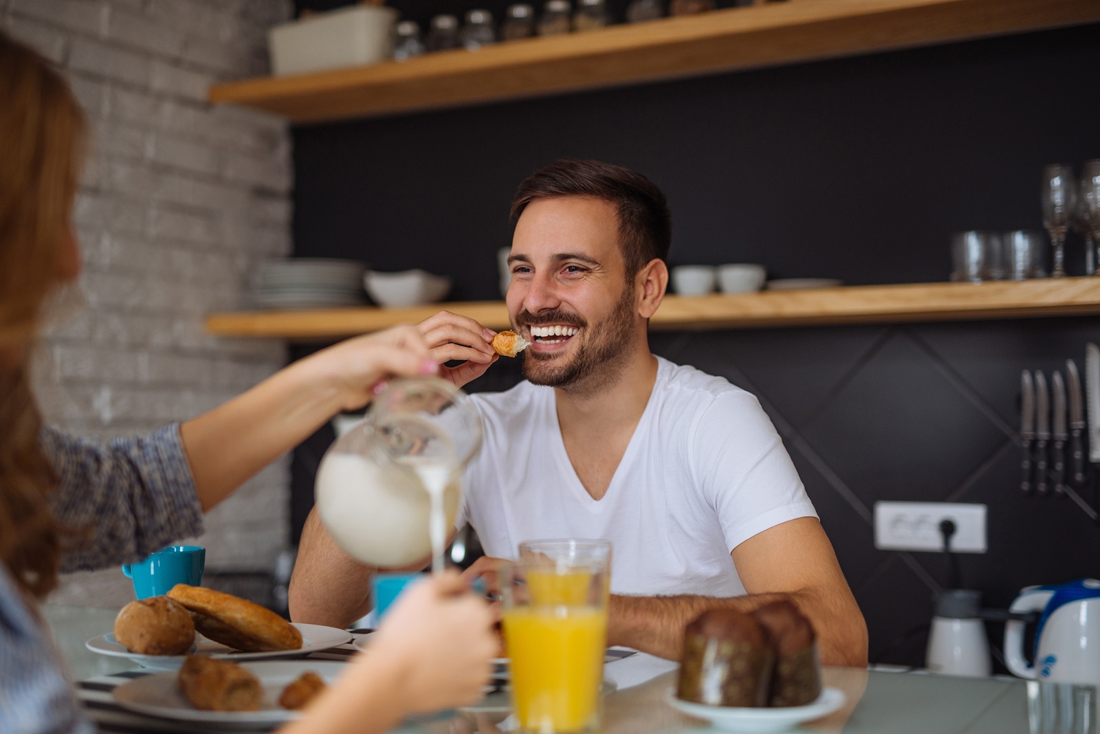 Handsome man enjoying breakfast with his girlfriends at home.