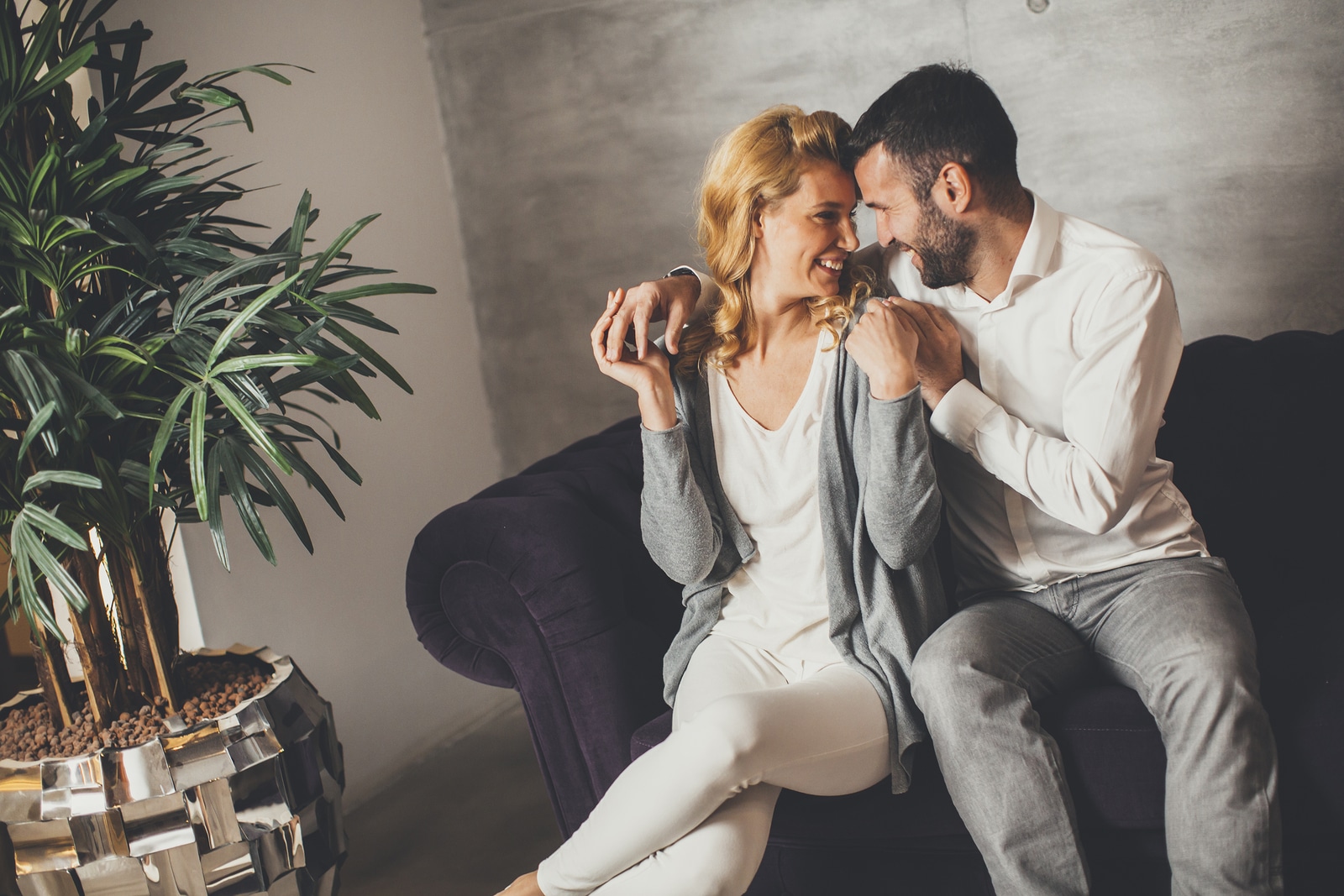 Portrait of cheerful couple sitting in sofa at home