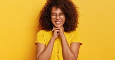 Mulher negra sorrindo de olhos fechados