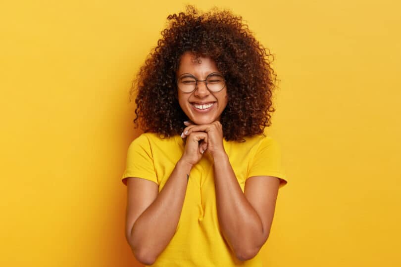 Mulher negra sorrindo de olhos fechados