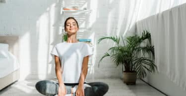 Mulher sentada em posição de meditação respirando profundamente.