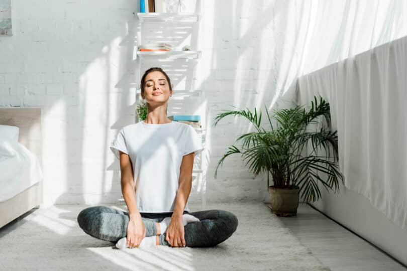 Mulher sentada em posição de meditação respirando profundamente.