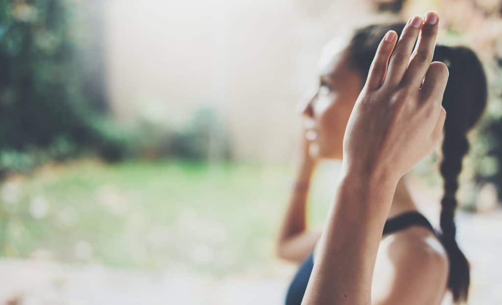 Closeup view of female hands.Gorgeous young woman practicing yoga indoor.Beautiful girl smiling during practice class.Calmness and relax, female happiness concept.Horizontal, blurred background