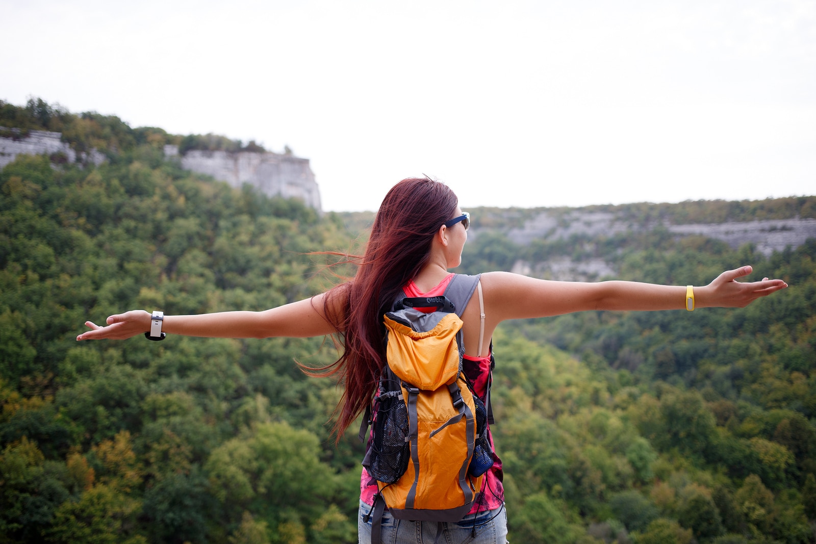 Brunette with travel backpack back on background of mountains