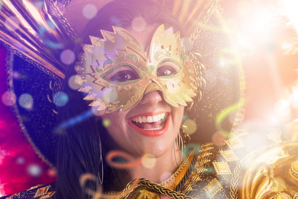 Mulher com máscara de carnaval sorrindo.