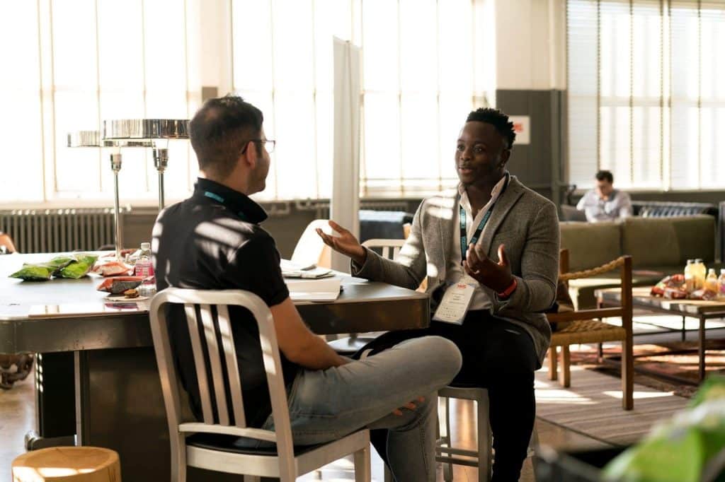 Dois homens sentados na cadeira conversando. 