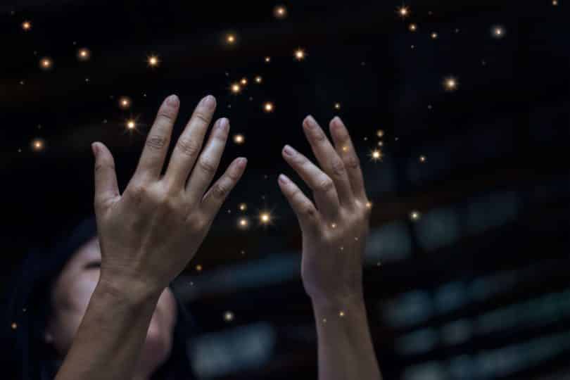 Mulher com as mãos para cima em meio as estrelas do céu