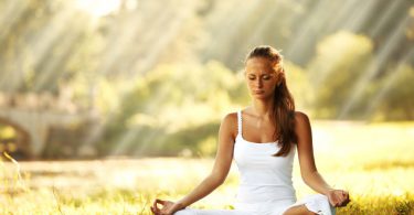 Mulher meditando em um campo aberto.