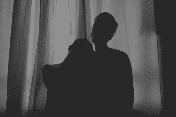 Silhueta de um casal em frente de cortinas da janela em um quarto escuro