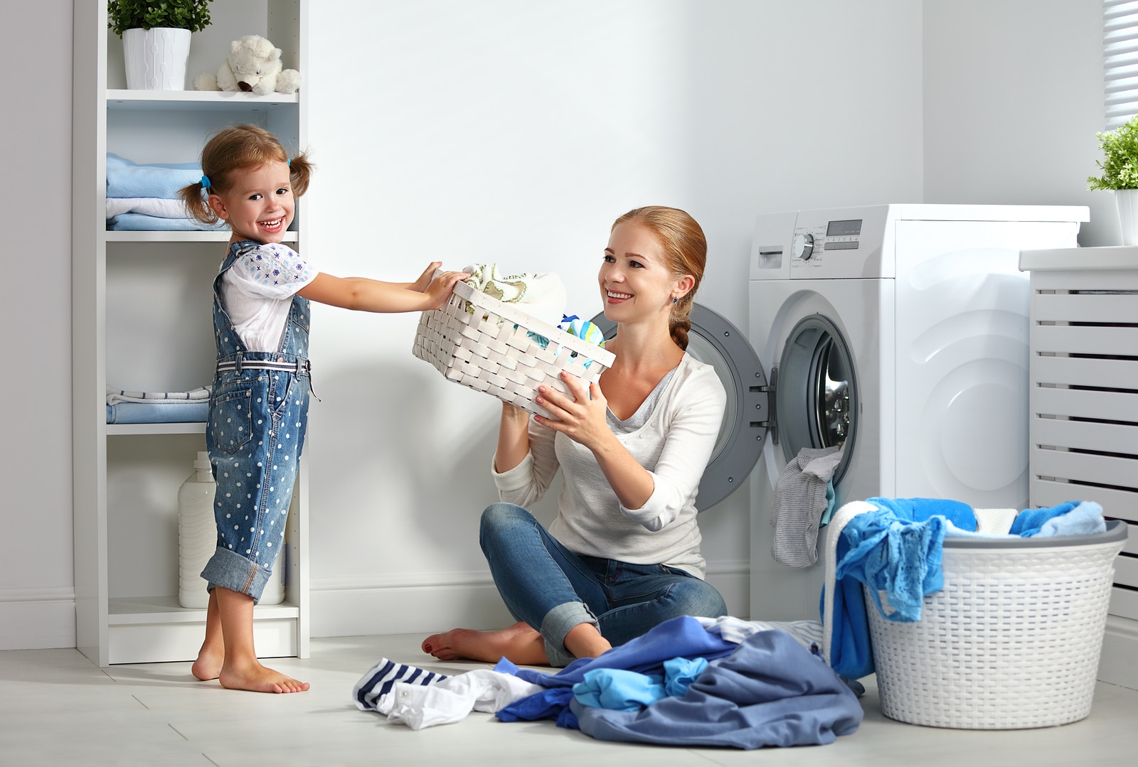 Menina sorrindo com a sua mãe na lavanderia da casa.