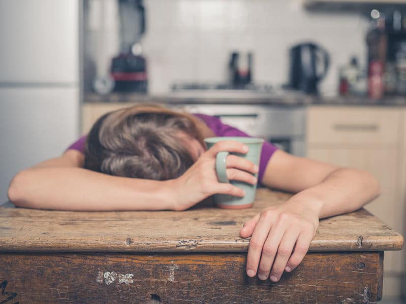 Mulher apoiada na mesa com caneca na mão