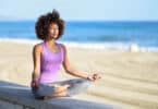 Mulher negra fazendo meditação à beira da praia