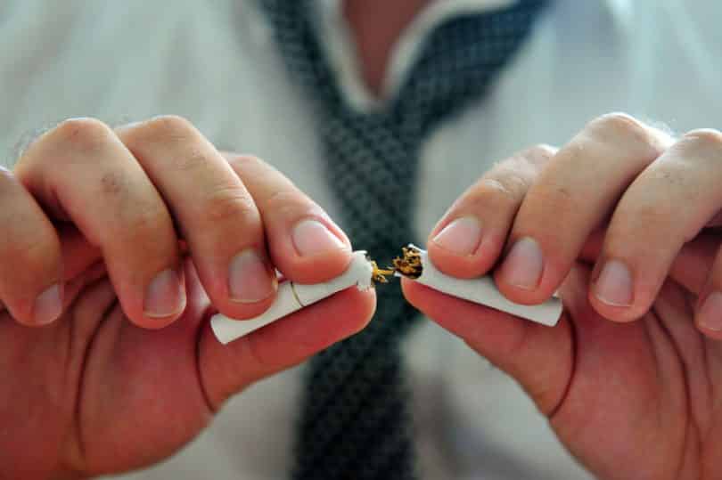 Mãos de homem quebrando cigarro no meio