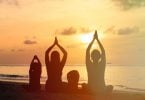 Família praticando Yoga juntos em uma praia.