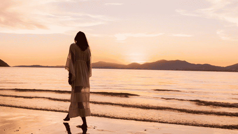 Mulher caminhando na beira da praia