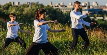 Imagem de três pessoas praticando Tai Chi Chuan ao ar livre