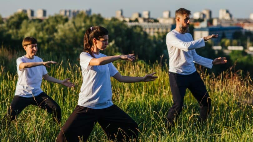 Imagem de três pessoas praticando Tai Chi Chuan ao ar livre