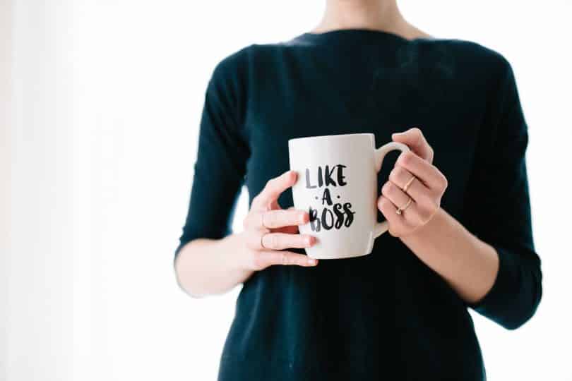 Mulher segurando uma caneca que está escrito em inglês "like a boss"