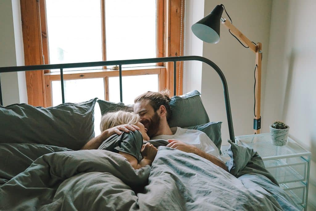 Casal deitado na cama ao lado de um abajur