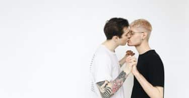 Casal de homens de mãos dadas se beijando