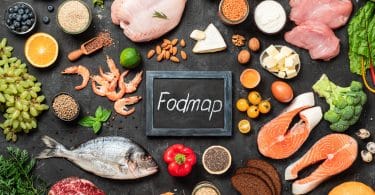 Carne de frango, peixe, frutos do mar, vegetais e frutas e palavras Fodmap no centro, em fundo escuro.