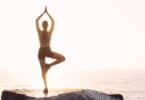 Imagem de uma mulher fazendo Yoga em cima de uma pedra de frente para o mar