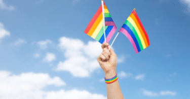 Bandeira LGBTQIAP+ levantada por uma mão
