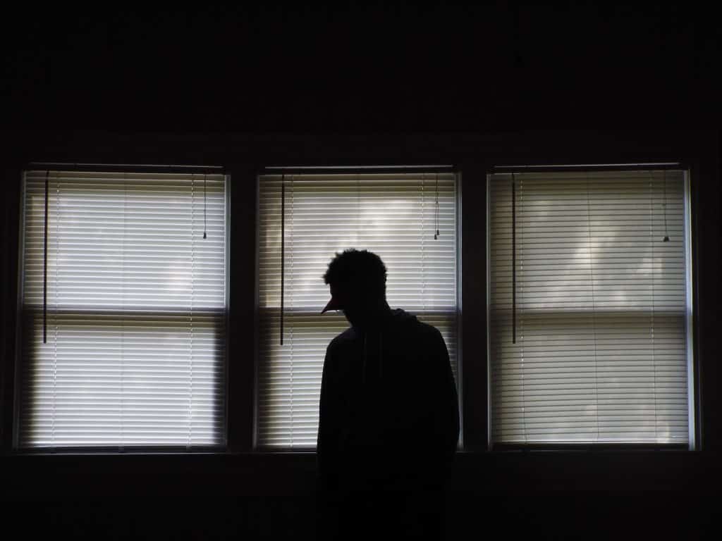 Homem em frente a uma janela de cabeça baixa