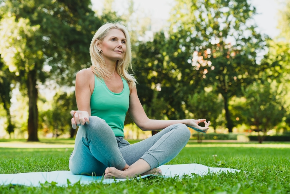 Velha meditando em um parque