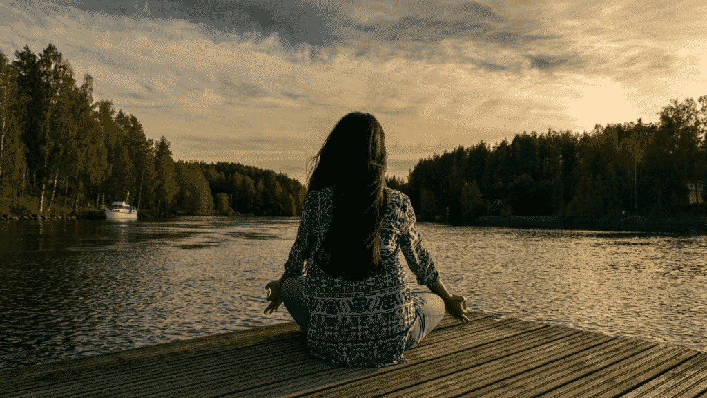 Mulher meditando em um convés na represa