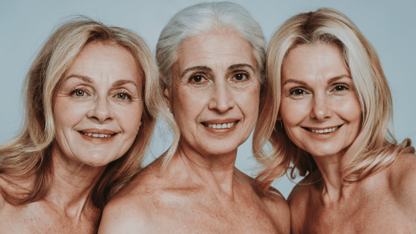 Três mulheres por volta dos cinquenta anos sorrindo.