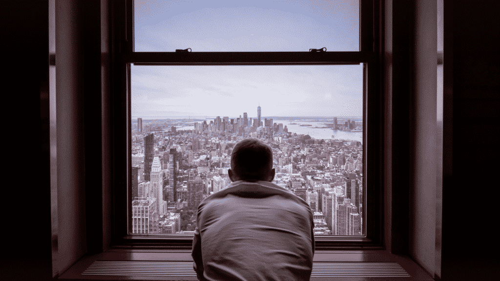 Homem olhando pela janela pensativo