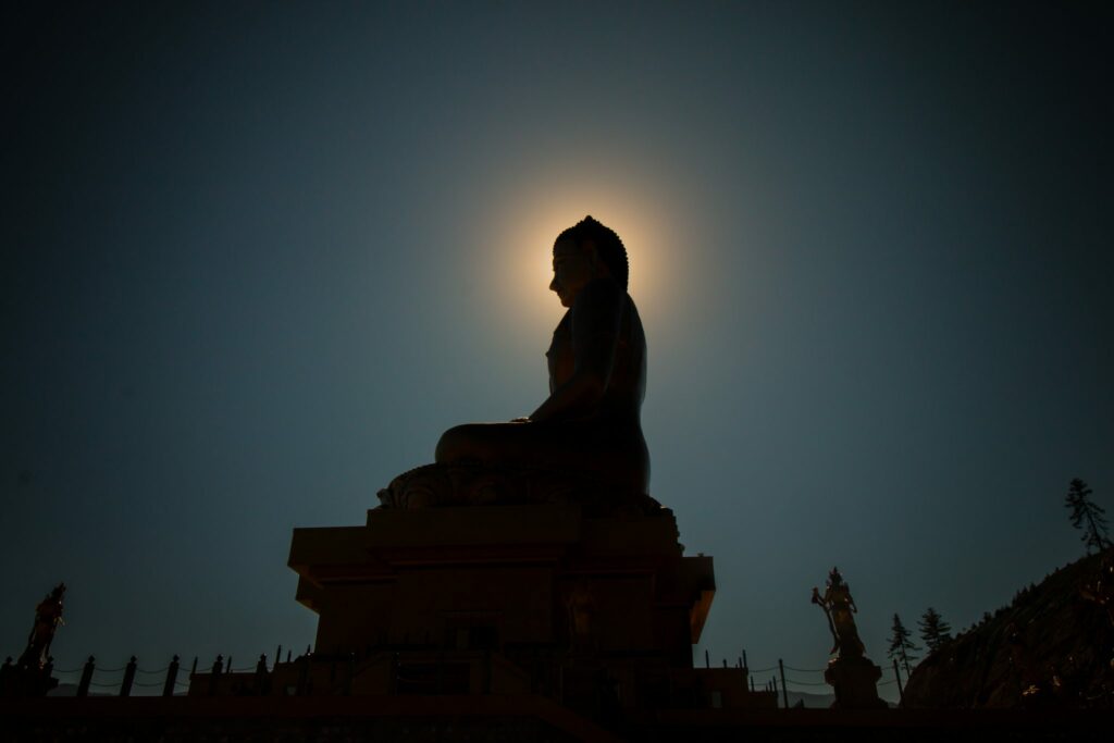 Silhueta de uma estátua de buda sentado em pose de meditação.