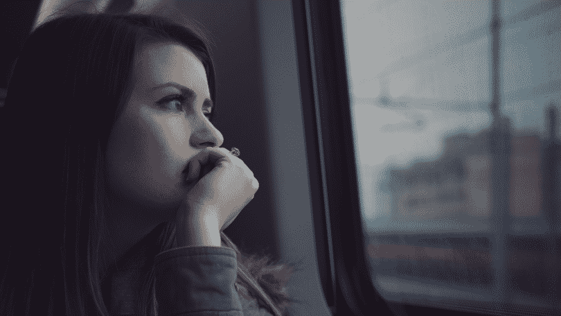Mulher olhando pensativa pela janela