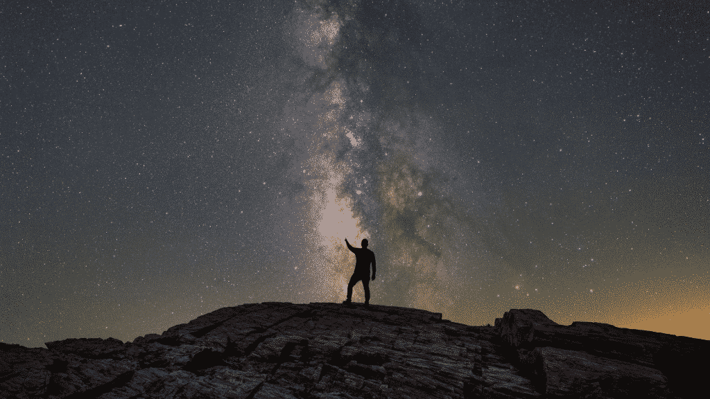 Silhueta de um homem apontado para as estrelas