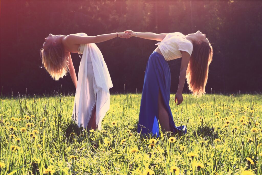 Duas mulheres de mãos dadas jogando os corpos para trás.