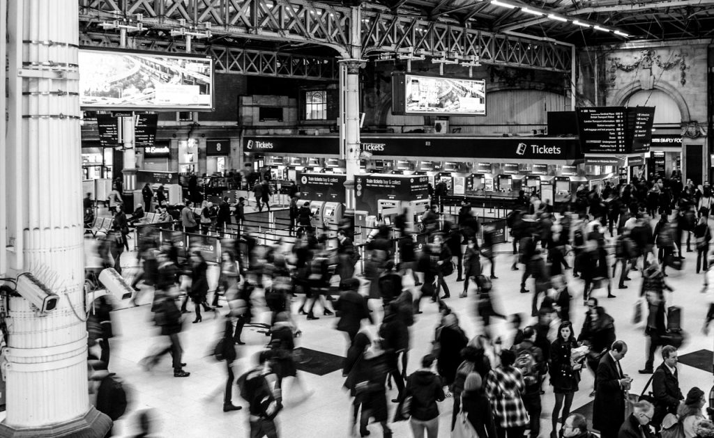 Várias pessoas andando apressadamente em uma estação de trem 