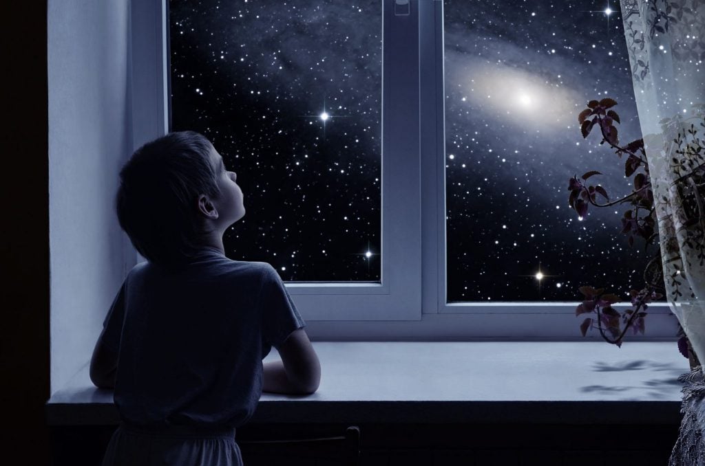 Criança olhando as estrelas pela janela.