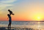 Mãe levantando filho na beira da praia