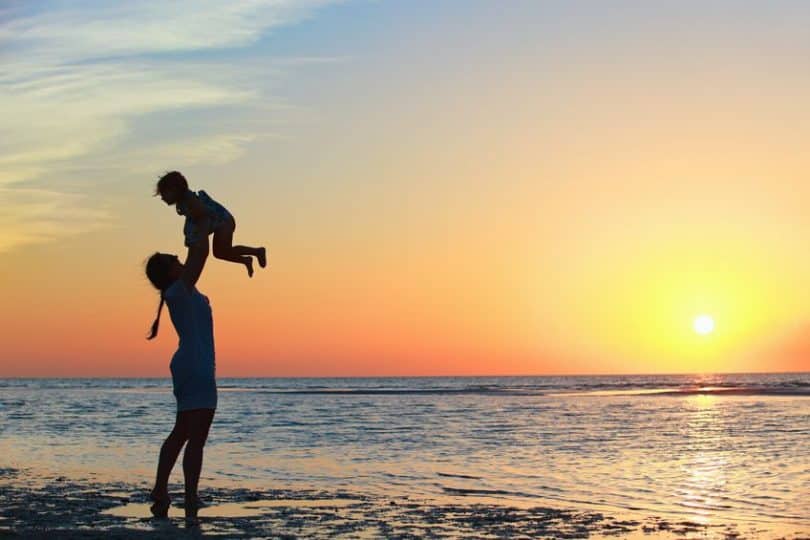 Mãe levantando filho na beira da praia