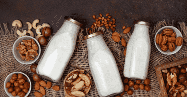 Sementes e castanhas em uma mesa e recipientes de vidro com leite