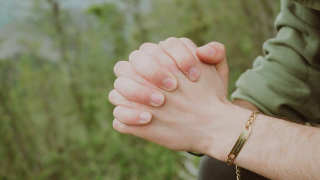 Imagem das mãos de uma pessoa orando, trazendo o conceito de fé, espiritualidade e gratidão.