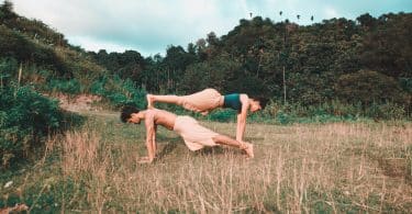 Homem e mulher em uma posição de yoga em um gramado