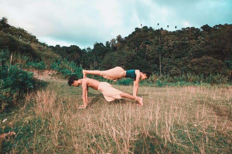 Homem e mulher em uma posição de yoga em um gramado