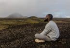 Homem sentado em um chão de terra olhando para o horizonte